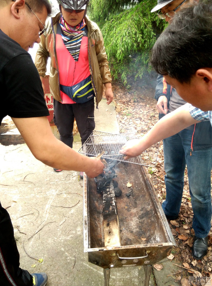 對面,燒烤爐擺好,從灶中取出已起火的炭球和木條,放上架子.